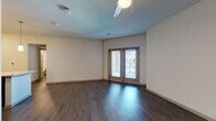 This well-designed single-floor residence offers a contemporary open-concept layout that seamlessly connects the living, dining, and kitchen areas. Rich, dark hardwood-style flooring flows throughout the main living spaces, complementing the clean, neutral wall tones and creating a warm, modern aesthetic.

The kitchen is a standout feature, showcasing dark espresso cabinetry that extends to the ceiling for maximum storage, a striking white subway tile backsplash, and gleaming granite countertops. A central island with a granite surface provides additional prep space and casual seating, while stainless steel appliances — including a refrigerator, range, and microwave — complete the contemporary look. Stylish pendant lighting illuminates the island with an elegant touch.

The spacious living area is bright and airy, featuring a ceiling fan and French doors that open to a private balcony, inviting natural light and outdoor views. Bedrooms are finished with plush carpet for added comfort.

The bathrooms are thoughtfully designed with granite countertops and dark-framed vanity mirrors. The primary bathroom features a double-sink vanity with dark cabinetry, a tiled walk-in shower, and direct access to a walk-in closet with built-in shelving — offering both style and practical storage throughout.