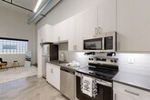 This one-bedroom, one-bathroom loft unit at 3511 Tire Towne Road in Winston-Salem, NC, offers a distinctive industrial-chic aesthetic rooted in the heritage of the Whitaker Park development. Soaring ceilings with exposed ductwork and pendant lighting run throughout the open layout, lending a dramatic sense of vertical space. Polished concrete floors extend across the main living areas, reflecting light and reinforcing the loft's modern industrial character.

The entry hallway leads into the combined living and kitchen area, where a galley-style kitchen features crisp white cabinetry, subway tile backsplash, and a full suite of stainless steel appliances including a refrigerator, electric range, built-in microwave, and dishwasher. A grid-pane window at the end of the living area allows natural light to filter in, brightening the expansive open space.

The bedroom is a calm, well-proportioned retreat with tall ceilings, polished concrete floors, and a double-door closet providing ample storage. The bathroom is clean and functional, featuring a full soaking tub with tile surround and brushed nickel fixtures. Additional conveniences include in-unit laundry and two closets. The unit's overall design balances raw architectural character with modern finishes throughout.