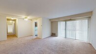 Located at 1070 Greenwall Pl in Frederick, MD, this single-floor residence offers a practical and well-organized layout across two bedrooms, one bathroom, a living room, kitchen, and hallway. The living room is generously sized, featuring neutral-toned carpet, a ceiling fan, and a large sliding glass door with vertical blinds that fills the space with natural light and provides outdoor views. The front entry opens directly into this open, airy area. The kitchen is equipped with warm wood cabinetry, light countertops, a double sink, and white appliances including a range and refrigerator. Wood-style flooring and a window overlooking the exterior add practicality and brightness to the space. Both bedrooms are carpeted and finished in neutral tones. The primary bedroom is notably spacious and includes a ceiling fan, while the second bedroom features a window with natural light and ample wall space. One bedroom includes a large sliding-door closet for storage. The bathroom is neatly appointed with a dark-toned vanity, a wide mirror with overhead lighting, and tile flooring. A connecting hallway ties all rooms together efficiently, contributing to the home's cohesive and functional flow throughout.