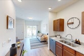 Located at 4299 N Towne Ct in Windsor, Wisconsin, this 2-bedroom, 1-bathroom residence delivers a thoughtfully organized single-floor layout with clean, contemporary finishes throughout. The kitchen is a functional centerpiece, featuring warm-toned shaker cabinetry, granite countertops, a double stainless steel sink, and a full suite of stainless steel appliances including a range, microwave, dishwasher, and refrigerator. Light hardwood-style flooring runs through the kitchen, living area, hallway, and bathroom, creating a cohesive and easy-to-maintain foundation. The living room is bright and welcoming, anchored by a sliding glass door that fills the space with natural light and provides views of the surrounding landscape. The primary bedroom offers a ceiling fan, a large window with outdoor views, plush carpeting, and access to a dedicated walk-in closet with wire shelving for ample storage. The shared bathroom continues the granite countertop theme with a warm wood vanity, a shower-tub combination, and hardwood-style flooring. A connecting hallway links all rooms efficiently. Recessed lighting and neutral wall tones throughout contribute to a clean, modern ambiance well-suited for everyday living.