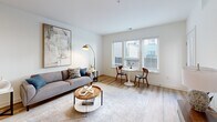 Located at 26 Locust St in Carteret, NJ, this well-appointed one-bedroom, one-bathroom residence offers a thoughtfully designed open-concept layout. Light-toned hardwood flooring runs throughout, complementing the bright, neutral color palette that defines the space.

The combined living, dining, and kitchen area forms the heart of the home. The kitchen is outfitted with white upper cabinetry, gray lower cabinetry, stainless steel appliances including a gas range and dishwasher, a white subway tile backsplash, and a central island with quartz countertops and bar seating. Pendant lighting accents the island, while the living area benefits from large windows that invite abundant natural light. A full-light glass door opens directly to a private balcony.

The bedroom is a calm, well-lit retreat featuring wide windows with outdoor views and direct access to a walk-in closet with built-in shelving. The bathroom includes a soaking tub and shower combination with white subway tile surround and matte black fixtures. Additional conveniences include a dedicated laundry area, a hallway connecting the main rooms, and two closets for ample storage. The entrance provides a welcoming transition into this clean, modern living space.