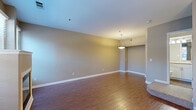 This two-story residence in Greenwood Village, Colorado offers a well-designed layout spread across two levels. The main floor features a bright, open living area with rich hardwood flooring, a built-in fireplace flanked by large windows that fill the space with natural light, and a seamless connection to the kitchen. The kitchen is appointed with white cabinetry, granite countertops, stainless steel appliances, and a window above the sink. A pendant-lit dining area with hardwood floors adds to the functionality of the main level, which also includes a half bathroom with a white vanity and modern fixtures. Upstairs, the spacious bedroom impresses with vaulted ceilings and an arched window that brings in abundant natural light, complemented by plush carpeting. A second fireplace adds warmth and character to the bedroom. The upper level also features a walk-in closet with built-in shelving, providing generous storage. Three bathrooms total serve the home, each featuring white vanities, large mirrors, and contemporary lighting. A dedicated laundry area houses a full-size washer and dryer. The thoughtful two-floor design balances living and private spaces efficiently throughout this Greenwood Village home.