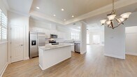 Located at 11225 Linden Dr in Spring Hill, FL, this single-story home offers a thoughtfully designed floor plan with four bedrooms, two bathrooms, and a dedicated laundry room. Light wood-look flooring flows throughout the main living areas, complemented by neutral walls and ceiling fans in each room.

The open-concept kitchen is a standout, featuring white shaker cabinetry, granite countertops, a central island, stainless steel appliances, and recessed lighting. Decorative columns frame the transition into the adjoining living and dining areas, where a tray ceiling with crown molding and a chandelier add architectural elegance. Plantation shutters allow for natural light control throughout.

The primary bedroom features a tray ceiling and direct access to the outdoors via a glass-panel door. The primary bathroom is finished with a granite-topped white vanity, brass-accented hardware, and large-format travertine-style tile flooring. Spacious closets, including a walk-in with wire shelving, provide generous storage.

Secondary bedrooms are well-sized with ample closet space and natural light. The laundry room includes upper cabinetry for added storage. The attached garage features an epoxy-coated speckled floor and an automatic opener, offering a clean and functional utility space.