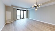 Located on the 20th floor at 517 Richmond St in London, Ontario, this contemporary 1-bedroom, 1-bathroom unit offers a well-appointed open-concept layout finished with light hardwood flooring and neutral tones throughout. The kitchen is a standout feature, showcasing sleek white cabinetry, a mosaic tile backsplash, stainless steel appliances — including a French door refrigerator, electric range, and built-in microwave — and a large central island with a quartz countertop, undermount sink, and modern pendant lighting. The kitchen flows seamlessly into the combined dining and living area, which is bathed in natural light and opens to a balcony through floor-to-ceiling sliding glass doors. The spacious bedroom includes a dedicated closet and a large window with balcony access, providing ample natural light. The bathroom is elegantly designed with marble-look tile flooring, a floating vanity with a round mirror, stylish pendant lighting, and a tiled accent wall. Additional highlights include a dedicated in-suite laundry room with built-in shelving and a separate closet for storage. The unit's clean, modern aesthetic and functional layout make it a refined urban living space.