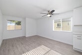 This single-story unit offers a thoughtfully designed layout that maximizes its compact footprint. Light wood-tone luxury vinyl flooring runs continuously throughout the space, creating a cohesive and clean aesthetic. Crisp white walls and multiple windows fitted with blinds allow natural light to flow generously through each room, enhancing the sense of openness.

The living area is a welcoming space anchored by a ceiling fan with integrated lighting, providing both comfort and illumination. Two windows frame the room on adjacent walls, offering views of surrounding greenery and keeping the space bright throughout the day.

The kitchen is well-equipped and modern, featuring white shaker-style cabinetry, white quartz countertops, and a full suite of stainless steel appliances including a range, over-the-range microwave, and dishwasher. A window above the sink adds natural light to the workspace, making it both functional and pleasant.

The bedroom is a comfortably sized retreat with its own ceiling fan, a window with outdoor views, and the same consistent flooring found throughout the unit.

The bathroom is finished in a clean, contemporary style with a white shaker vanity, quartz countertop, framed mirror, brushed nickel fixtures, and a shower-tub combination, completing this well-maintained and move-in ready space.