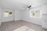 This single-story unit offers a thoughtfully designed layout that maximizes its compact footprint. Light wood-tone luxury vinyl flooring runs continuously throughout the space, creating a cohesive and clean aesthetic. Crisp white walls and multiple windows fitted with blinds allow natural light to flow generously through each room, enhancing the sense of openness.

The living area is a welcoming space anchored by a ceiling fan with integrated lighting, providing both comfort and illumination. Two windows frame the room on adjacent walls, offering views of surrounding greenery and keeping the space bright throughout the day.

The kitchen is well-equipped and modern, featuring white shaker-style cabinetry, white quartz countertops, and a full suite of stainless steel appliances including a range, over-the-range microwave, and dishwasher. A window above the sink adds natural light to the workspace, making it both functional and pleasant.

The bedroom is a comfortably sized retreat with its own ceiling fan, a window with outdoor views, and the same consistent flooring found throughout the unit.

The bathroom is finished in a clean, contemporary style with a white shaker vanity, quartz countertop, framed mirror, brushed nickel fixtures, and a shower-tub combination, completing this well-maintained and move-in ready space.
