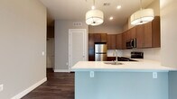Located at 2001 W Cold Spring in Baltimore, MD, this single-floor residence offers a thoughtfully designed layout with modern finishes throughout. The open-concept kitchen serves as a central hub, featuring rich dark wood cabinetry, stainless steel appliances including a refrigerator, range, microwave, and dishwasher, and a large island with a white quartz countertop and undermount sink. Stylish pendant lighting illuminates the space, complemented by recessed lighting and durable wood-look flooring. The kitchen flows seamlessly into the living area, creating an inviting, connected atmosphere. The bedrooms are generously sized with plush carpeting, soft neutral wall tones, and large windows fitted with roller shades that invite abundant natural light and offer views of surrounding greenery. Elevated ceilings and ceiling fans add to the airy feel of the sleeping quarters. The bathrooms are well-appointed, with one featuring a full soaking tub with white tile surround, dark wood vanity, and a framed mirror, while another offers a glass-enclosed walk-in shower and natural light from large windows overlooking lush outdoor scenery. Wood-look flooring runs through the bathrooms, tying together the cohesive, contemporary aesthetic found throughout the entire residence.