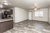 This two-floor residence offers a thoughtfully laid-out living environment with a blend of practical features and comfortable design. The main level showcases an open-concept kitchen and living area, where rich dark cabinetry with granite-look countertops pairs with black appliances, including a refrigerator, range, and dishwasher. Wood-look plank flooring flows throughout the kitchen and living spaces, complemented by textured ceilings and ceiling fans that add character to each room. A chandelier over the kitchen peninsula adds a touch of elegance, while a window in the living area allows natural light to brighten the space.

The bedrooms are carpeted for comfort and feature ceiling fans, generous closet space with built-in shelving, and easy access to the bathrooms. The bathrooms are well-appointed with dark vanity cabinetry, framed mirrors, and tub-shower combinations, all finished with the same wood-look flooring found elsewhere in the home.

A dedicated laundry area houses a full-size washer and dryer alongside additional shelving, providing excellent utility and storage. The lower level features a secondary kitchen or kitchenette space with matching dark cabinetry and wood-look flooring, making it a versatile area suited for a variety of uses. Throughout both floors, the design maintains a cohesive, neutral palette with dark trim accents.
