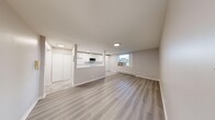 This 2-bedroom, 1-bathroom unit offers a thoughtfully organized single-floor layout with a clean, contemporary aesthetic throughout. The open-concept kitchen and living area form the heart of the unit, with the kitchen featuring white flat-panel cabinetry extending to the ceiling for ample storage, light quartz countertops, a marble-style tile backsplash, white appliances including a range and refrigerator, and a built-in microwave. Polished grey tile flooring in the kitchen transitions seamlessly into light-toned luxury vinyl plank flooring that flows through the living area and bedrooms. The living room is a bright, open space with recessed lighting and a window providing natural light and outdoor views. Both bedrooms are comfortably sized, with the primary bedroom featuring windows that allow in natural light and a closet for storage. The secondary bedroom also includes windows with views to the outdoors. The bathroom is finished with large-format marble-look tile lining the tub surround, giving it a clean, modern feel. Baseboard heating is present throughout, and the neutral warm-grey wall palette ties the entire unit together in a cohesive, move-in-ready presentation.