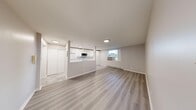 This 2-bedroom, 1-bathroom unit offers a thoughtfully organized single-floor layout with a clean, contemporary aesthetic throughout. The open-concept kitchen and living area form the heart of the unit, with the kitchen featuring white flat-panel cabinetry extending to the ceiling for ample storage, light quartz countertops, a marble-style tile backsplash, white appliances including a range and refrigerator, and a built-in microwave. Polished grey tile flooring in the kitchen transitions seamlessly into light-toned luxury vinyl plank flooring that flows through the living area and bedrooms. The living room is a bright, open space with recessed lighting and a window providing natural light and outdoor views. Both bedrooms are comfortably sized, with the primary bedroom featuring windows that allow in natural light and a closet for storage. The secondary bedroom also includes windows with views to the outdoors. The bathroom is finished with large-format marble-look tile lining the tub surround, giving it a clean, modern feel. Baseboard heating is present throughout, and the neutral warm-grey wall palette ties the entire unit together in a cohesive, move-in-ready presentation.