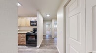Located in Edmonds, WA, this 2-bedroom, 1-bathroom residence at Park 212 offers a thoughtfully designed single-floor layout that makes efficient use of its space. The interior features warm wood-look hard surface flooring throughout the main living areas, complemented by plush carpeting in both bedrooms, creating a comfortable and cohesive atmosphere.

The kitchen is equipped with light wood cabinetry, granite-style countertops, and black appliances including a range and over-the-range microwave. It connects seamlessly to the main hallway, which leads to the living room and bedrooms. The living room offers access to a private balcony, extending the living space outdoors.

Both bedrooms are well-proportioned and carpeted, each featuring windows that bring in natural light and views of the surrounding greenery. The primary bedroom is generously sized, providing ample room for furnishings.

The full bathroom is finished with a wood-toned vanity, granite-style countertop, a large mirror, and a tub/shower combo. A dedicated laundry area houses a stacked washer and dryer unit, adding everyday convenience. Additional storage is available via a closet. The overall aesthetic is clean, neutral, and move-in ready.