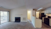 Located at 1025 Avent Hill in Raleigh, NC, this single-floor residence offers a well-designed layout with a comfortable, functional flow throughout. The living room is a standout space, featuring vaulted ceilings, a classic wood-burning fireplace with a white mantle, and plush carpeting underfoot. A sliding glass door opens to a private balcony with tree-lined views, filling the room with natural light. Adjacent to the living room, a half-wall partition separates the galley-style kitchen, which is equipped with white cabinetry, a double sink, black appliances including a refrigerator and electric range, and wood-look flooring for easy maintenance. A dedicated dining area with a ceiling fan sits just off the kitchen. The bedrooms are generously sized, carpeted, and filled with natural light from large windows overlooking lush greenery. One bedroom features a spacious walk-in closet. The bathrooms include full tub-shower combinations with built-in shelving niches and clean white finishes. A dedicated laundry area with an included washer adds everyday convenience. Throughout the home, neutral tones and consistent finishes create a cohesive, move-in-ready atmosphere.