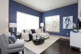 This single-story residence showcases a cohesive contemporary design highlighted by rich dark hardwood flooring, crown molding, and a carefully coordinated navy and neutral color palette. The kitchen is a standout feature, outfitted with dark espresso cabinetry extending to the ceiling, granite countertops, and a full suite of stainless steel appliances including a gas range, built-in microwave, and French door refrigerator. A peninsula with pendant lighting and bar seating connects the kitchen to the adjacent dining and living areas, creating an open, social layout ideal for entertaining.

The living area is bathed in natural light from multiple large windows and a glass door, complemented by bold navy accent walls and elegant drapery. Two bedrooms provide comfortable retreats, each featuring plush carpeting, large windows with outdoor views, and generous walk-in closets with built-in wire shelving systems. The bathrooms are finished with granite-topped vanities, dark cabinetry, and tiled tub-shower combinations, maintaining the refined aesthetic found throughout the residence. Overall, the space exudes a polished, modern ambiance with thoughtful attention to detail.