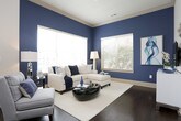 This single-story residence showcases a cohesive contemporary design highlighted by rich dark hardwood flooring, crown molding, and a carefully coordinated navy and neutral color palette. The kitchen is a standout feature, outfitted with dark espresso cabinetry extending to the ceiling, granite countertops, and a full suite of stainless steel appliances including a gas range, built-in microwave, and French door refrigerator. A peninsula with pendant lighting and bar seating connects the kitchen to the adjacent dining and living areas, creating an open, social layout ideal for entertaining.

The living area is bathed in natural light from multiple large windows and a glass door, complemented by bold navy accent walls and elegant drapery. Two bedrooms provide comfortable retreats, each featuring plush carpeting, large windows with outdoor views, and generous walk-in closets with built-in wire shelving systems. The bathrooms are finished with granite-topped vanities, dark cabinetry, and tiled tub-shower combinations, maintaining the refined aesthetic found throughout the residence. Overall, the space exudes a polished, modern ambiance with thoughtful attention to detail.