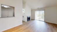 Located at 2631 Midway Branch Dr in Odenton, MD, this one-bedroom, one-bathroom residence offers a well-designed layout across a single floor. The living room serves as the heart of the home, showcasing soaring vaulted ceilings that amplify the sense of space, light hardwood flooring, and a tile-surround fireplace as a central focal point. A sliding glass door floods the area with natural light and opens to a private balcony overlooking lush greenery. An open pass-through connects the living area to the kitchen, which features crisp white shaker cabinetry, granite-style countertops, a stainless steel sink, and stainless steel appliances including a dishwasher. The entry area continues the hardwood flooring and benefits from vaulted ceilings and track lighting, lending an airy, welcoming feel. The bedroom is carpeted for comfort and offers a large window with outdoor views and ample wall space for furnishings. The bathroom is clean and functional, appointed with a white vanity, solid countertop, and a large mirror. Throughout, the home maintains a bright, neutral palette that creates a cohesive and inviting atmosphere.