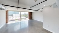 This urban loft masterfully combines industrial character with contemporary design, creating a distinctive living space full of personality and modern functionality. The main living area makes a strong first impression with its polished concrete floors, exposed black pipe conduits running along the ceiling, and expansive floor-to-ceiling sliding glass doors that flood the space with natural light and frame sweeping city views. A prominent exposed brick column anchors the open-plan layout, adding warmth and texture to the otherwise clean, neutral palette.

The kitchen is well-appointed with white shaker cabinetry, bold black granite countertops, and stainless steel appliances, all set against a backdrop of original exposed brick walls that lend an authentic, historic character. A dedicated laundry room provides added convenience.

The bedrooms continue the industrial aesthetic with polished concrete floors, ceiling fans, exposed ductwork, and brick accent walls. Each bedroom is served by a walk-in closet, offering generous storage. The bathrooms echo the loft's design language — one features a floating double vanity, large mirror, and exposed brick with overhead ductwork, while a second offers a glass-enclosed shower alongside additional brick detailing. Throughout, the interplay of raw materials and refined finishes creates a cohesive, urban ambiance.