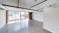 This urban loft masterfully combines industrial character with contemporary design, creating a distinctive living space full of personality and modern functionality. The main living area makes a strong first impression with its polished concrete floors, exposed black pipe conduits running along the ceiling, and expansive floor-to-ceiling sliding glass doors that flood the space with natural light and frame sweeping city views. A prominent exposed brick column anchors the open-plan layout, adding warmth and texture to the otherwise clean, neutral palette.

The kitchen is well-appointed with white shaker cabinetry, bold black granite countertops, and stainless steel appliances, all set against a backdrop of original exposed brick walls that lend an authentic, historic character. A dedicated laundry room provides added convenience.

The bedrooms continue the industrial aesthetic with polished concrete floors, ceiling fans, exposed ductwork, and brick accent walls. Each bedroom is served by a walk-in closet, offering generous storage. The bathrooms echo the loft's design language — one features a floating double vanity, large mirror, and exposed brick with overhead ductwork, while a second offers a glass-enclosed shower alongside additional brick detailing. Throughout, the interplay of raw materials and refined finishes creates a cohesive, urban ambiance.