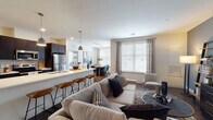 Located at 1252 Osgood St in North Andover, MA, this well-appointed single-floor residence showcases a thoughtfully designed open-concept layout with contemporary finishes throughout. Rich hardwood-style flooring flows seamlessly across the main living areas, anchoring the space with warmth and visual continuity.

The open living, dining, and kitchen area serves as the heart of the home. The kitchen is equipped with stainless steel appliances, dark cabinetry, white quartz countertops, and a breakfast bar with seating — all illuminated by pendant lighting. The dining area is adjacent, highlighted by a large window that fills the space with natural light. The living room offers generous proportions and additional window access for a bright, airy feel.

The primary bedroom features a striking teal accent wall, multiple windows with sheer drapery, plush carpeting, and access to a walk-in closet. Its en-suite bathroom includes a dark-cabinet vanity with a white countertop and a private water closet. A secondary bedroom is equally comfortable, with large windows, neutral tones, and soft carpeting. A second full bathroom provides a tub-shower combination with clean white tile and dark cabinetry. The overall ambiance is modern, clean, and inviting throughout.