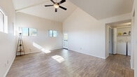 Located at 7007 E Gold Dust Ave in Scottsdale, Arizona, this single-story home combines open, airy design with practical functionality. The main living area is an immediate standout, boasting dramatically vaulted ceilings with a ceiling fan overhead and wood-style plank flooring throughout. Multiple windows allow generous natural light to pour in, creating a warm, sun-drenched atmosphere. A glass-paned exterior door leads to the outdoors, enhancing the connection between interior and exterior spaces.

The kitchen is well-appointed with rich dark wood cabinetry, light countertops, and a full suite of black appliances including a range, microwave, refrigerator, and dishwasher. Recessed lighting and wood-style flooring complete the functional yet stylish cooking space.

The bedroom features plush carpeting, a ceiling fan, and a large window framing outdoor views, offering a comfortable and serene retreat. An additional carpeted room provides flexible space for various uses. The bathroom includes a full tub and shower combo with white tile surround, a vanity with dark wood cabinetry, and wood-style flooring, maintaining the cohesive aesthetic found throughout the home.

Overall, the space presents a clean, neutral palette with thoughtful finishes, making it a versatile and inviting home in the heart of Scottsdale.