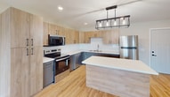 This contemporary apartment offers 840 square feet of thoughtfully designed living space on a single floor. The open-concept layout seamlessly integrates the living room and kitchen, creating a spacious feel. The kitchen is a highlight, featuring sleek light wood cabinetry, stainless steel appliances, and a stylish subway tile backsplash. A modern rectangular light fixture adds a touch of elegance.

The apartment boasts two bedrooms, including a primary bedroom of 120 square feet, and two full bathrooms. Both bathrooms feature modern vanities, large mirrors, and attractive lighting. One bathroom includes a bathtub with a shower curtain.

Throughout the apartment, warm-toned hardwood flooring adds a touch of natural beauty and complements the neutral wall colors. Large windows, including a sliding glass door leading to a balcony, flood the space with natural light and offer views of the surrounding area.

Additional features include recessed lighting, wall-mounted air conditioning units, and ample closet space. The apartment's clean lines, neutral color palette, and contemporary fixtures create a modern and inviting living environment.