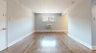 Located at 335 E Mount Airy Ave in Philadelphia's Mount Airy neighborhood, this one-bedroom, one-bathroom unit offers a thoughtfully organized single-floor layout. Rich hardwood flooring flows throughout the living and bedroom areas, lending warmth and continuity to the space. The living room is open and bright, with neutral gray walls, clean white baseboards, and a wall-mounted air conditioning unit beneath a window that brings in natural light. A closet and entry door are neatly positioned along one wall, providing practical storage from the moment you enter.

The spacious primary bedroom continues the hardwood flooring and features a ceiling fan, a window with an exterior view, and a double closet, offering comfortable storage. An additional door connects the bedroom to the hallway, which leads to the bathroom. The bathroom is finished with white subway-style tile and a bold black-and-white decorative tile border accent, giving it a clean, classic look with a tub-shower combination.

The kitchen is distinct in its tile flooring and features warm-toned wood cabinetry, a blue-gray glass tile backsplash, black appliances including a gas range and refrigerator, and an over-range microwave. The overall unit presents a clean, functional aesthetic throughout.