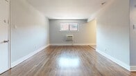 Located at 335 E Mount Airy Ave in Philadelphia's Mount Airy neighborhood, this one-bedroom, one-bathroom unit offers a thoughtfully organized single-floor layout. Rich hardwood flooring flows throughout the living and bedroom areas, lending warmth and continuity to the space. The living room is open and bright, with neutral gray walls, clean white baseboards, and a wall-mounted air conditioning unit beneath a window that brings in natural light. A closet and entry door are neatly positioned along one wall, providing practical storage from the moment you enter.

The spacious primary bedroom continues the hardwood flooring and features a ceiling fan, a window with an exterior view, and a double closet, offering comfortable storage. An additional door connects the bedroom to the hallway, which leads to the bathroom. The bathroom is finished with white subway-style tile and a bold black-and-white decorative tile border accent, giving it a clean, classic look with a tub-shower combination.

The kitchen is distinct in its tile flooring and features warm-toned wood cabinetry, a blue-gray glass tile backsplash, black appliances including a gas range and refrigerator, and an over-range microwave. The overall unit presents a clean, functional aesthetic throughout.