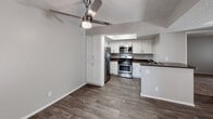 Located at 11750 Mount Vernon Ave in Grand Terrace, California, this single-floor unit offers a well-organized layout with thoughtfully updated finishes throughout. The living area features rich wood-look vinyl flooring and a ceiling fan with light fixture, creating a comfortable and functional space. Vertical blinds on a sliding glass door provide access to the exterior while allowing natural light to fill the room. The kitchen is equipped with stainless steel appliances, including a gas range, microwave, and refrigerator, complemented by white cabinetry, dark countertops, and a peninsula that connects seamlessly to the living area. Bedrooms are carpeted and bathed in natural light from windows dressed with vertical blinds. One bedroom includes a built-in closet with shelving, while another features an open vanity area with white cabinetry, a wide mirror, and a lighted fixture — offering a semi-private dressing space. The bathroom includes a full tub and shower combination with clean white surrounds. A second bathroom presents a similar layout with wood-look flooring, a vanity with dark countertop, and a separate water closet. Textured ceilings are consistent throughout, and neutral gray walls provide a versatile backdrop across all rooms.