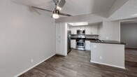 Located at 11750 Mount Vernon Ave in Grand Terrace, California, this single-floor unit offers a well-organized layout with thoughtfully updated finishes throughout. The living area features rich wood-look vinyl flooring and a ceiling fan with light fixture, creating a comfortable and functional space. Vertical blinds on a sliding glass door provide access to the exterior while allowing natural light to fill the room. The kitchen is equipped with stainless steel appliances, including a gas range, microwave, and refrigerator, complemented by white cabinetry, dark countertops, and a peninsula that connects seamlessly to the living area. Bedrooms are carpeted and bathed in natural light from windows dressed with vertical blinds. One bedroom includes a built-in closet with shelving, while another features an open vanity area with white cabinetry, a wide mirror, and a lighted fixture — offering a semi-private dressing space. The bathroom includes a full tub and shower combination with clean white surrounds. A second bathroom presents a similar layout with wood-look flooring, a vanity with dark countertop, and a separate water closet. Textured ceilings are consistent throughout, and neutral gray walls provide a versatile backdrop across all rooms.