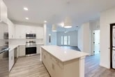 Located at 25 Silver Moon Circle in St. Augustine, FL, this well-appointed single-story home offers a thoughtfully designed open-concept floor plan with 2 bedrooms and 2 bathrooms. The heart of the home is a bright, modern kitchen featuring white shaker cabinetry, stainless steel appliances, a spacious center island with quartz countertops, and stylish pendant lighting — all flowing seamlessly into the combined dining and living area. French doors in the living room invite natural light and provide outdoor access, while a ceiling fan adds to the comfortable, airy atmosphere throughout. Light wood-tone flooring runs consistently across the main living areas, enhancing the clean, contemporary aesthetic. The primary bedroom offers a generous walk-in closet with wire shelving, while the second bedroom benefits from a large window with serene outdoor views and a ceiling fan. Both bathrooms are finished with quartz vanity countertops and modern fixtures; the full bath includes a tub-shower combination with warm tile surround and dual windows for natural light. Additional conveniences include four closets, a dedicated laundry area with stacked washer/dryer, and a utility room, making this home as functional as it is stylish.