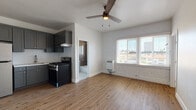 Located in the Koreatown neighborhood of Los Angeles, Unit 402 at 260 S Mariposa Ave presents a well-appointed single-floor residence with clean, modern updates throughout. The open living area features warm-toned hardwood-style flooring, crisp white walls with an exposed brick accent, and a wood-blade ceiling fan that adds a touch of character. A wall-mounted heater and bright windows allow natural light to fill the space while offering views of the surrounding neighborhood.

The kitchen is efficiently designed with charcoal-gray shaker cabinets extending to the ceiling, a white subway tile backsplash, light countertops, a stainless steel refrigerator, and a gas range — offering both style and practicality for everyday cooking.

The bedroom is generously proportioned with the same hardwood-style flooring and features a mirrored sliding-door closet that enhances the sense of space. The bathroom is tastefully finished with large hexagonal marble-look floor tiles, a marble-tiled shower and tub surround, a gray vanity with chrome fixtures, and contemporary wall lighting, creating a clean and polished feel.

Throughout the unit, the consistent use of light tones and quality finishes gives the space a cohesive, refreshed aesthetic well-suited for comfortable urban living in Los Angeles.
