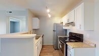 Located at 4711 Bay Run Dr. in Columbus, Ohio, this single-floor residence offers a well-organized, open-concept layout with a clean and functional design. The living area is bright and spacious, featuring light-toned wood-style flooring, neutral walls, and a textured ceiling. A ceiling fan adds comfort to the main living space, which flows seamlessly into the kitchen via a half-wall breakfast bar. The kitchen is well-appointed with white cabinetry, granite-style countertops, stainless steel appliances including a full-size refrigerator and electric range, a built-in range hood, and track lighting overhead. A sink with under-cabinet storage completes the functional cooking space. The bedrooms offer a comfortable retreat — one features plush carpeting and a window with outdoor views, while another showcases the same light wood-style flooring found throughout the common areas, along with a bright window that invites natural light. The bathroom is finished with tile flooring, a white vanity with under-sink storage, a framed mirror, and a shower-tub combination. A built-in shelving unit is visible in the hallway, adding practical storage. Overall, the space presents a tidy, move-in-ready environment with consistent neutral tones and modern updates throughout.