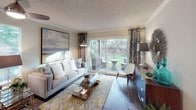 Located at 11733 NE 131st Place in Kirkland, Washington, this single-floor residence offers a well-organized layout designed for comfortable everyday living. The living room serves as the centerpiece of the home, featuring rich hardwood-style flooring, crown molding, and a large sliding glass door that opens directly onto a private patio. The outdoor space overlooks a lush green landscape, allowing natural light to fill the interior and creating a seamless indoor-outdoor connection. The galley-style kitchen is efficiently arranged with wood-toned cabinetry, dark countertops, a double-basin sink, and a full suite of appliances including a refrigerator, electric range, and built-in microwave. The bedroom is carpeted and restful in atmosphere, with a wide window framing verdant outdoor views, soft neutral walls, and a mirrored sliding-door closet with built-in shelving for organized storage. The full bathroom features a single-sink vanity with wood cabinetry and dark countertop, a tub and shower combination with a curtained enclosure, and warm overhead lighting. Throughout the residence, a cohesive neutral color palette, textured ceilings, and thoughtful design details contribute to a calm and functional living environment.