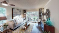 Located at 11733 NE 131st Place in Kirkland, Washington, this single-floor residence offers a well-organized layout designed for comfortable everyday living. The living room serves as the centerpiece of the home, featuring rich hardwood-style flooring, crown molding, and a large sliding glass door that opens directly onto a private patio. The outdoor space overlooks a lush green landscape, allowing natural light to fill the interior and creating a seamless indoor-outdoor connection. The galley-style kitchen is efficiently arranged with wood-toned cabinetry, dark countertops, a double-basin sink, and a full suite of appliances including a refrigerator, electric range, and built-in microwave. The bedroom is carpeted and restful in atmosphere, with a wide window framing verdant outdoor views, soft neutral walls, and a mirrored sliding-door closet with built-in shelving for organized storage. The full bathroom features a single-sink vanity with wood cabinetry and dark countertop, a tub and shower combination with a curtained enclosure, and warm overhead lighting. Throughout the residence, a cohesive neutral color palette, textured ceilings, and thoughtful design details contribute to a calm and functional living environment.