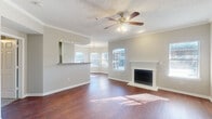 Located at 8383 El Mundo St in Houston, TX, this single-story, 3-bedroom, 2-bathroom home offers a well-designed layout that balances comfort and functionality. The living room serves as the heart of the home, showcasing rich hardwood-style flooring, crown molding, a textured ceiling, a ceiling fan with light fixture, and a classic white-mantled fireplace flanked by windows that invite ample natural light. A hallway connects the living area to the bedrooms, maintaining a smooth flow throughout the residence. The kitchen is equipped with rich cherry-toned cabinetry, granite countertops, stainless steel appliances including a range and microwave, a tile backsplash, and light tile flooring. It opens to the dining area through an arched entryway, adding architectural charm. The bedrooms feature plush carpeting, ceiling fans, and sliding glass doors or windows with outdoor views. The primary bedroom offers a generous footprint with access to natural light. Both bathrooms are finished with warm stone-toned tile surrounds, soaking tubs, and rich wood vanity cabinetry with granite countertops. Two closets and a hallway complete this efficient and inviting floor plan.