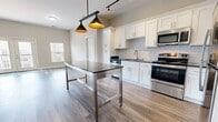This contemporary apartment showcases a thoughtfully designed open-concept layout, maximizing space and functionality. The living area is bright and airy, with large windows and a glass door leading to a private balcony, allowing natural light to flood the space. Wood-look flooring throughout adds warmth and continuity.

The kitchen is a standout feature, boasting white cabinetry, subway tile backsplash, and stainless steel appliances. A central island with pendant lighting provides additional workspace and casual dining options. The bathroom continues the modern aesthetic with a sleek vanity, large mirror, and a glass-enclosed shower with marble-look tiling.

Bedrooms are generously sized with ample closet space, including a walk-in closet in at least one room. The neutral color palette throughout creates a calming atmosphere and allows for personalization. Additional amenities include in-unit laundry facilities and smart home features like programmable thermostats.

This apartment combines style and practicality, offering a turnkey living experience in a desirable urban setting.