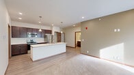 Located at 9941 S 37th St in Lincoln, Nebraska, this single-floor, 2-bedroom, 2-bathroom home offers a thoughtfully designed open-concept layout. The kitchen serves as the centerpiece, featuring a large island with a built-in sink, dark espresso cabinetry, stainless steel appliances including a refrigerator, range, and microwave, and light hardwood-style flooring. Pendant lighting above the island adds a polished touch. The kitchen flows seamlessly into the living room, which is finished with plush neutral carpeting and large windows fitted with vertical blinds that allow abundant natural light. Both bedrooms are carpeted and include ceiling fans, vertical blinds for light control, and access to well-organized closets with built-in shelving and hanging rods — one of which is a generous walk-in. The two bathrooms are clean and functional, with dark wood vanities, white countertops, and a tub-shower combination. A dedicated in-unit laundry room houses a full-size Whirlpool washer and dryer with overhead shelving for added convenience. Throughout the home, warm wood-toned door frames and baseboards provide a cohesive, inviting aesthetic. The overall ambiance is bright, clean, and move-in ready.
