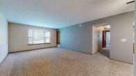 This single-floor unit at 5770 S Winds Dr in Mentor-on-the-Lake, Ohio, offers a practical and well-organized layout across several interconnected rooms. The spacious living area is finished with neutral-toned carpeting and features a ceiling fan with integrated lighting. A two-tone color scheme, with soft blue-gray accent walls contrasting against lighter neutral tones, carries throughout the main living spaces, lending a cohesive aesthetic to the interior.

The living area benefits from a wide multi-pane window that allows natural light to filter into the room, offering views of the surrounding greenery. The open sightline from the living area toward the kitchen provides a sense of connectivity throughout the unit. The kitchen is equipped with warm oak-toned cabinetry, light countertops, a double sink, and black appliances including a gas range, dishwasher, and a stainless steel refrigerator. Light wood-look flooring in the kitchen adds a clean contrast to the carpeted areas.

Multiple bedrooms provide comfortable, carpeted spaces, each with windows admitting natural light and closet access. The bathroom features wood-look flooring, a wood-toned vanity with a large mirror, and a tub-shower combination.