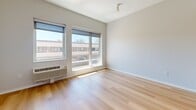 This efficiently designed studio unit at 337 Seventh St W, Unit 213, in Saint Paul, Minnesota, offers a thoughtfully organized layout across a single floor. The open-concept living area is bathed in natural light from large windows that frame views of the surrounding neighborhood, creating a bright and airy atmosphere. Light-toned hardwood flooring runs consistently throughout the space, lending a clean, cohesive feel to every room.

The kitchenette is well-appointed with white upper cabinetry, light wood lower cabinets, a subway tile backsplash, and a full suite of stainless steel appliances including a refrigerator, oven, microwave, and sink. Track lighting overhead adds functional illumination to the cooking area.

The living space is open and versatile, with neutral white walls and a wall-mounted HVAC unit beneath the windows for year-round climate control. The entry hallway is lined with modern wood-paneled closet doors, providing generous storage for a unit of this scale. A dedicated closet further enhances storage options.

The bathroom features wood-toned flooring consistent with the rest of the unit, a walk-in shower stall, and clean, minimal finishes. The overall design aesthetic is contemporary and minimalist, making effective use of every square foot in a practical, livable layout.