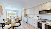 Located in Sweetwater, FL, this well-appointed 2-bedroom, 3-bathroom residence offers a thoughtfully designed single-floor layout with a clean, contemporary aesthetic throughout. The open-concept kitchen and dining area serve as the heart of the home, featuring light wood cabinetry that extends to the ceiling, white quartz countertops, a subway tile backsplash, stainless steel appliances, and warm hardwood-style flooring that flows seamlessly into the living and dining spaces. A glass-top dining table and modern furnishings complement the bright, airy atmosphere created by recessed lighting overhead. The primary bedroom is a serene retreat, bathed in natural light from large windows framing lush tropical palm views. It connects to a sleek en-suite bathroom with dual under-mount sinks, light wood vanity cabinetry, stone-look quartz countertops, matte black fixtures, and a marble-tiled walk-in shower. The second bedroom is equally inviting, with generous natural light, a ceiling fan, and tropical outlooks. All bathrooms maintain a consistent modern design language. A private balcony offers breathtaking views of a resort-style pool surrounded by swaying palms and open Florida skies, completing this vibrant South Florida residence.