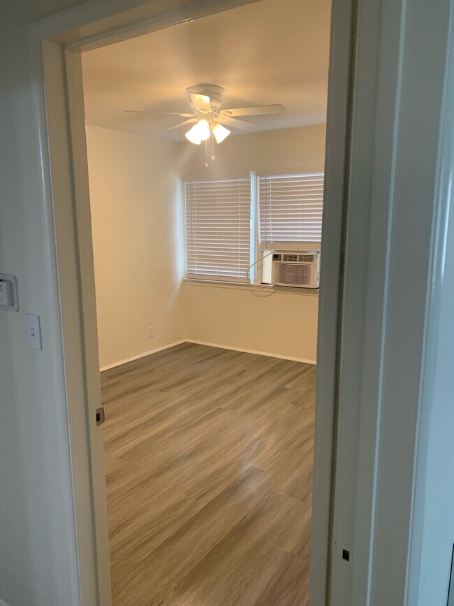 Bedroom with fan, window a/c unit, and blinds. - 130 S Del Mar Ave