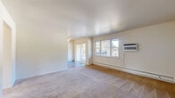 Located at 510 Maloney Rd in Poughkeepsie, NY, this two-bedroom, one-bathroom unit offers a comfortable and functional single-floor layout. The living areas feature neutral-toned carpeting and crisp white walls, creating a clean and inviting atmosphere. Large windows throughout the unit invite generous amounts of natural light, while wall-mounted air conditioning units and baseboard heating provide year-round climate control. A sliding glass door in the main living area opens to a private balcony, offering pleasant outdoor views of the surrounding greenery. The second living space flows openly toward the kitchen, which features hardwood-style flooring, white cabinetry, and a stainless steel refrigerator with a ceiling fan overhead. Both bedrooms are well-proportioned and carpeted, each equipped with windows that frame outdoor views and baseboard heating for added comfort. The primary bedroom is generously sized and benefits from bright, sun-filled exposure. The full bathroom is neatly appointed with a white vanity, an oval mirror, and a tub-shower combo with clean white surrounds. Five closets distributed throughout the unit ensure excellent storage capacity, rounding out this practical and well-lit Poughkeepsie residence.