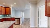 Located in Lawrenceville, GA, this well-appointed single-story home offers three bedrooms, three bathrooms, and a thoughtfully designed layout. The living room is a standout space, featuring a tray ceiling with crown molding, a classic white-mantled fireplace, and glass doors that invite natural light and outdoor views. Rich wood-look flooring flows throughout the main living areas, complemented by a neutral, light gray color palette.

The kitchen is a functional centerpiece, showcasing warm cherry wood cabinetry, granite countertops, a center island, a teal subway tile backsplash, and a full suite of stainless steel appliances. Crown molding and recessed lighting add a polished finish, with an arched passageway connecting the kitchen to the entrance foyer.

The bedrooms are carpeted for comfort, each equipped with a ceiling fan and ample natural light from large windows with views of surrounding greenery. The generously sized primary bedroom includes a walk-in closet with wire shelving. The bathrooms are finished with wood-look vinyl flooring, white cabinetry, granite counters, and tile-surround bathtubs. A dedicated laundry room with built-in shelving and washer hookups completes this practical and comfortable home.