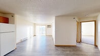This single-floor residential unit offers a well-organized layout designed for practical, comfortable living. The open living area is bright and spacious, featuring durable wood-look vinyl flooring, neutral-toned walls, and large sliding glass doors that lead to a balcony, flooding the space with natural light. Baseboard heating runs throughout the unit, ensuring consistent warmth. The kitchen is equipped with warm oak cabinetry, dark laminate countertops, a white electric range, and a built-in microwave, with an adjacent entry closet providing convenient storage near the main door. A dedicated in-unit laundry room houses a full-size washer and dryer alongside wire shelving for added utility. The bedrooms feature plush carpet, wood-trimmed windows with blinds, and built-in closets with wire rod shelving. A generously sized walk-in closet connects directly to one of the two full bathrooms, which includes a bathtub with grab bars, a toilet, and a single-sink vanity with a large mirror and warm cabinetry. The second bathroom mirrors this design, offering the same wood-toned vanity and granite-style countertop. Throughout the unit, consistent warm wood trim, textured ceilings in the living area, and a cohesive neutral palette create a clean, functional, and inviting atmosphere.