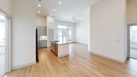 This single-story residence in Round Rock, Texas offers a thoughtfully designed open-concept layout filled with natural light and contemporary finishes throughout. Light wood-style flooring flows seamlessly across the main living areas, complementing the bright white walls and recessed lighting that create an airy, welcoming atmosphere.

The kitchen serves as a central hub of the home, featuring a central island with a granite countertop and undermount sink, gray shaker-style cabinetry, and a full suite of stainless steel appliances including a refrigerator, range, microwave, and dishwasher. The kitchen opens directly to the spacious living area, which is highlighted by soaring ceilings, a ceiling fan, and large windows that invite abundant natural light.

The bedrooms are finished with plush carpet and feature generous closet space with built-in shelving and hanging rods. Tall windows in the bedrooms provide pleasant outdoor views and additional natural light.

The bathrooms are well-appointed with granite-topped vanities, gray cabinetry, and wood-look flooring. The primary bathroom includes a glass-enclosed walk-in shower with tile surround, while the secondary bathroom offers a tub-shower combination. A dedicated mudroom/laundry area with built-in shelving and coat hooks adds practical functionality near the entry.