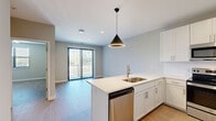 Located at 2120 NW Lowenstein in Lee's Summit, Missouri, this single-floor residence offers a clean, contemporary design with a neutral color palette and light wood-tone flooring that flows seamlessly throughout the space. The open-concept kitchen is a standout feature, equipped with white shaker-style cabinetry, quartz countertops, a central island with an undermount sink and pendant lighting, and a full suite of stainless steel appliances including a French door refrigerator with ice maker, range, microwave, and dishwasher. A dedicated laundry area is conveniently accessible from the kitchen. The living area is bright and open, featuring sliding glass doors with vertical blinds that provide access to an outdoor balcony and welcome an abundance of natural light. The bedrooms are well-proportioned, each featuring light wood flooring, neutral walls, and ample natural light from large windows fitted with blinds; one bedroom includes a ceiling fan and another features a spacious sliding-door closet. The bathroom is thoughtfully appointed with a wide white vanity, quartz countertop, large mirror, and a walk-in shower. Recessed lighting and modern fixtures throughout complete the polished, move-in-ready aesthetic of this well-designed residence.
