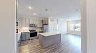 Located in Spring, TX, this well-designed 2-bedroom, 2-bathroom single-story residence offers a thoughtful layout with modern finishes throughout. The open-concept kitchen and living area serves as the heart of the home, featuring light wood-look flooring, recessed lighting, and a central island with a crisp white quartz countertop. The kitchen is equipped with stainless steel appliances, two-tone gray and light wood cabinetry, a subway tile backsplash, and pendant lighting, creating a clean, contemporary aesthetic. The living area flows seamlessly from the kitchen and benefits from abundant natural light through large windows with outdoor views. Both bedrooms feature ceiling fans, wide windows overlooking the outdoors, and wood-look flooring. The generously sized primary bedroom connects to a well-appointed en-suite bathroom showcasing marble-look tile flooring, a dual-sink vanity with gray cabinetry and black matte hardware, a large framed mirror, and a glass-enclosed walk-in shower. A spacious walk-in closet with dual hanging rods provides ample storage. The secondary bathroom offers a tiled tub-shower combination with matte black fixtures and open shelving. Two closets provide additional storage throughout the home.