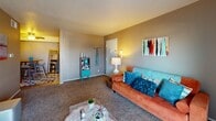 This single-floor unit offers a well-organized layout that connects living, dining, kitchen, and sleeping areas in a practical and cohesive flow. The living room serves as the heart of the space, featuring plush carpeting, neutral taupe walls, and large sliding glass doors that open onto a private balcony, filling the room with natural light and offering views of surrounding trees. The open feel is enhanced by a textured ceiling and ample wall space for décor.

The galley-style kitchen is efficiently designed with warm wood cabinetry, dark granite-style countertops, and tile flooring. Black appliances, including a range and refrigerator, are neatly integrated alongside a double basin sink, providing a functional cooking environment with generous storage.

The unit includes two carpeted bedrooms, each featuring neutral walls and windows that bring in natural light. Both rooms offer closet storage, with one bedroom featuring a spacious bi-fold door closet. The bathroom includes a vanity with dark countertop and an integrated sink, while a separate water closet houses the toilet, adding a layer of privacy and practicality. Tile flooring throughout the bathroom complements the overall design of the space.
