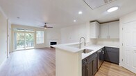 This multi-story home spans three floors, offering a well-organized layout designed for comfortable living. The entry-level floor houses a spacious attached garage equipped with an automatic opener, providing convenient access and additional storage. Carpeted staircases with clean white railings connect all three levels, lending a cohesive and polished look throughout.

The main living floor is the heart of the home, featuring an open-concept kitchen and living room combination. The kitchen showcases two-tone cabinetry — crisp white uppers paired with dark lower cabinets — complemented by white quartz countertops, a stainless steel sink, and a dishwasher. The adjoining living area is bathed in natural light from large windows and a sliding glass door that opens to a private balcony with neighborhood views. A fireplace with a white mantel serves as a focal point, while a ceiling fan and recessed lighting complete the space. The laundry room on this floor features ample upper and lower cabinetry with white quartz countertops.

The upper floor hosts two bedrooms, including a generously sized primary suite, and three full bathrooms. Each bathroom features dark vanity cabinetry, white countertops, and glass-enclosed showers. Bedrooms feature warm hardwood-style flooring and windows overlooking the surrounding greenery.