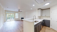 This multi-story home spans three floors, offering a well-organized layout designed for comfortable living. The entry-level floor houses a spacious attached garage equipped with an automatic opener, providing convenient access and additional storage. Carpeted staircases with clean white railings connect all three levels, lending a cohesive and polished look throughout.

The main living floor is the heart of the home, featuring an open-concept kitchen and living room combination. The kitchen showcases two-tone cabinetry — crisp white uppers paired with dark lower cabinets — complemented by white quartz countertops, a stainless steel sink, and a dishwasher. The adjoining living area is bathed in natural light from large windows and a sliding glass door that opens to a private balcony with neighborhood views. A fireplace with a white mantel serves as a focal point, while a ceiling fan and recessed lighting complete the space. The laundry room on this floor features ample upper and lower cabinetry with white quartz countertops.

The upper floor hosts two bedrooms, including a generously sized primary suite, and three full bathrooms. Each bathroom features dark vanity cabinetry, white countertops, and glass-enclosed showers. Bedrooms feature warm hardwood-style flooring and windows overlooking the surrounding greenery.