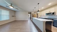 This thoughtfully designed one-bedroom, one-bathroom residence in High Point, NC offers a clean, modern aesthetic throughout its efficiently organized single-floor layout. The open-concept kitchen and living area serves as the heart of the home, anchored by a sleek kitchen island with a white quartz countertop and undermount sink, illuminated by stylish industrial pendant lights. The kitchen features two-tone cabinetry — crisp white upper cabinets paired with navy lower cabinets — complemented by a subway tile backsplash and stainless steel appliances including a refrigerator, range, and microwave. Wide-plank light hardwood flooring flows throughout the main living areas, adding warmth and continuity. A charming sliding barn door adds a rustic accent and connects to the private spaces. The spacious bedroom is carpeted for comfort, features natural light through a window with blinds, and is serviced by a ceiling fan. The walk-in closet is equipped with wire shelving for organized storage. The bathroom offers a clean, contemporary feel with a frameless sliding glass shower enclosure, white vanity with quartz countertop, and wood-look tile flooring. A dedicated laundry area with hookups rounds out this well-equipped and move-in-ready home.